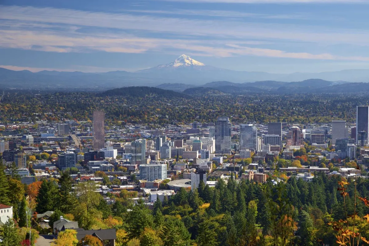 A breathtaking vista of Mount Hood and the downtown skyline surrounded by lush greenery and autumn foliage, embodying the beauty and recreational opportunities of Southeast Portland.